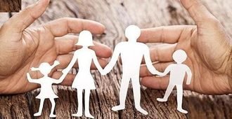 Des mains protègent une famille découpée dans du papier